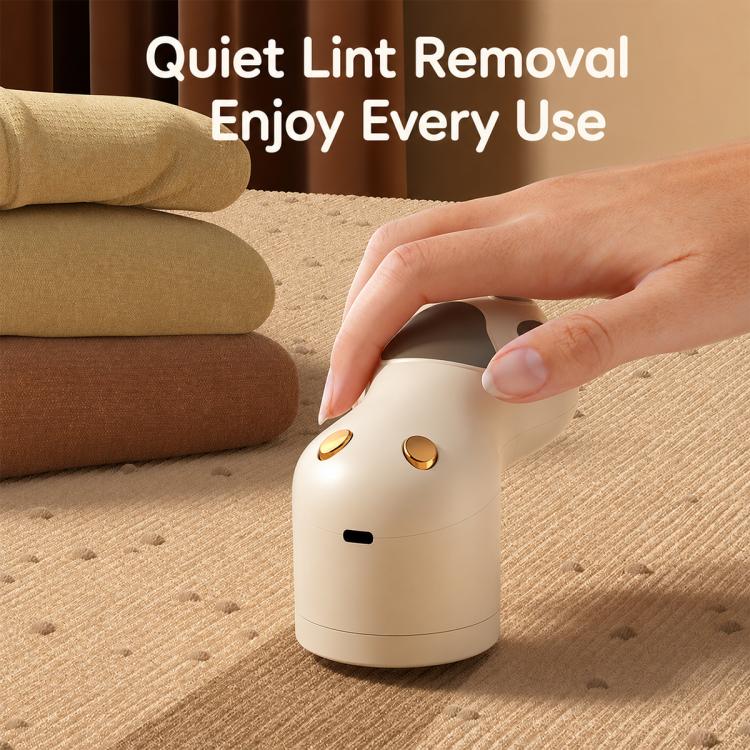 Off-white electric lint remover held in hand, rounded cat-paw pawprint body.