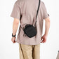 Black round crossbody bag with drawstring-style top, zipper pocket, worn crossbody