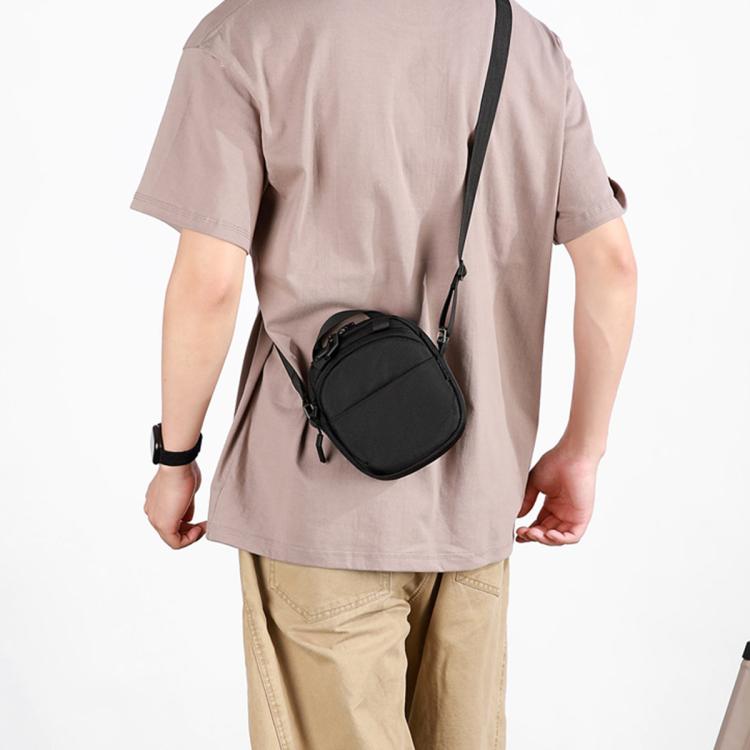 Black round crossbody bag with drawstring-style top, zipper pocket, worn crossbody