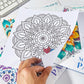 Mandala painting sheets with geometric flower pattern, hands holding one page