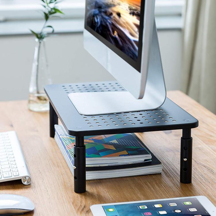 Black ventilated monitor stand with perforated shelf under a computer monitor