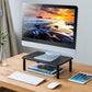 Black metal monitor stand with perforated cooling panel and open lower storage shelf