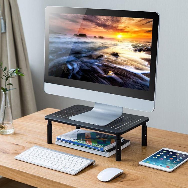 Black metal monitor stand with perforated cooling panel and open lower storage shelf
