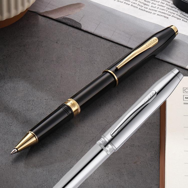 Black and silver metal rollerball pens with screw caps, lying on papers.