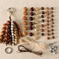 Natural seed bead charms set with assorted oval beads, cords, and metal ring