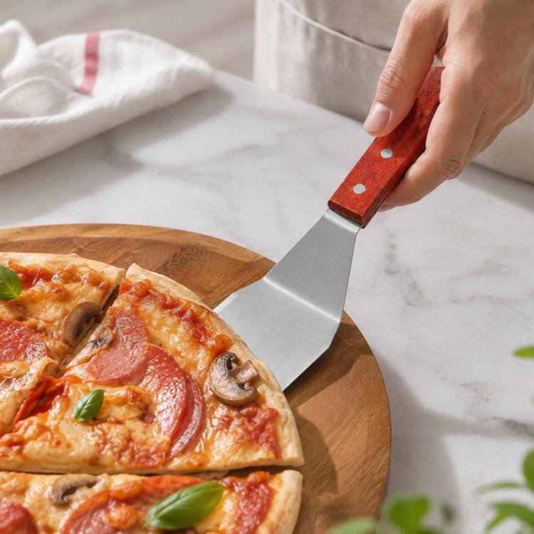 Stainless steel pizza spatula with wooden handle, lifting a slice from a wooden board
