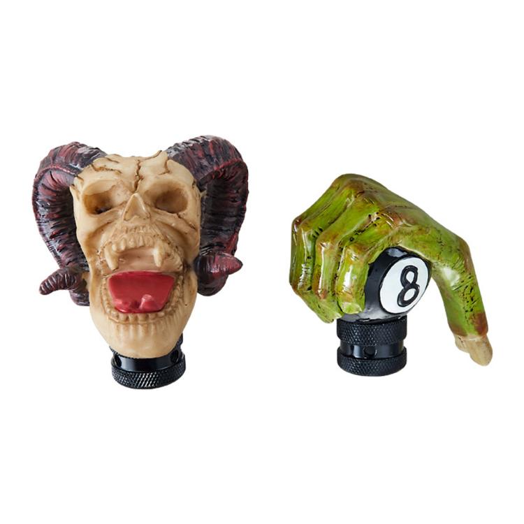 Pair of resin gear shift knobs: horned skull with red tongue and green 8-style head