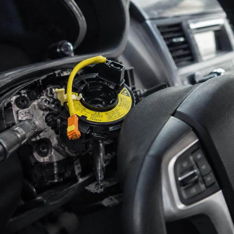 Steering wheel airbag clock spring spiral cable with yellow loop and orange connector, mounted