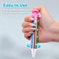 Pink-capped retractable click crayon held in hand, clear barrel with colored leads
