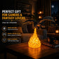 Black dragon night light with yellow flames on table with stack of books and mug.