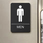 Black Braille sign with raised male icon, tactile dots, and MEN label.