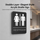 Black restroom Braille sign with raised male and female icons and RESTROOM label.
