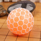 Orange anti-stress grape squeeze ball with white web pattern on tiled floor