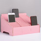 Pink multi-cell desktop phone stand with grid dividers holding three phones.