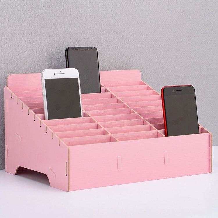 Pink multi-cell desktop phone stand with grid dividers holding three phones.