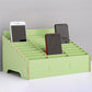 Green multi-cell desktop phone stand with grid dividers holding three phones.