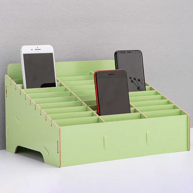 Green multi-cell desktop phone stand with grid dividers holding three phones.