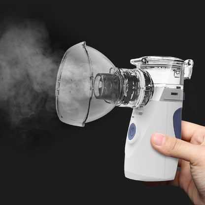 Handheld ultrasonic nebulizer with transparent mask cup releasing visible mist, white and blue