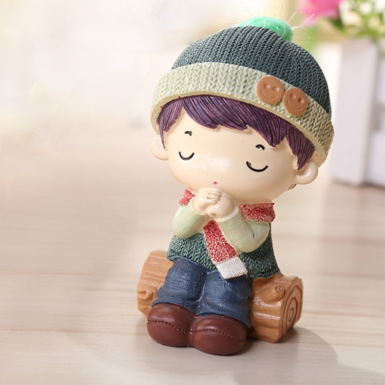 Resin child doll figurine in green knit cap, striped scarf, clasped hands, wooden base
