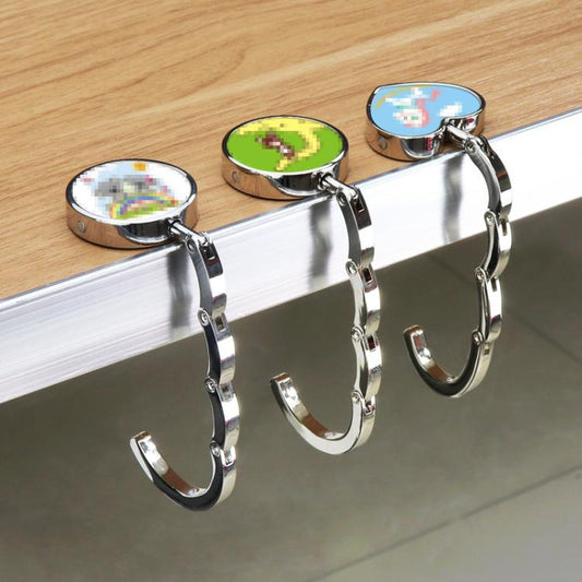 Set of chrome folding bag hangers with round bases, hook clips, and colorful disc tops