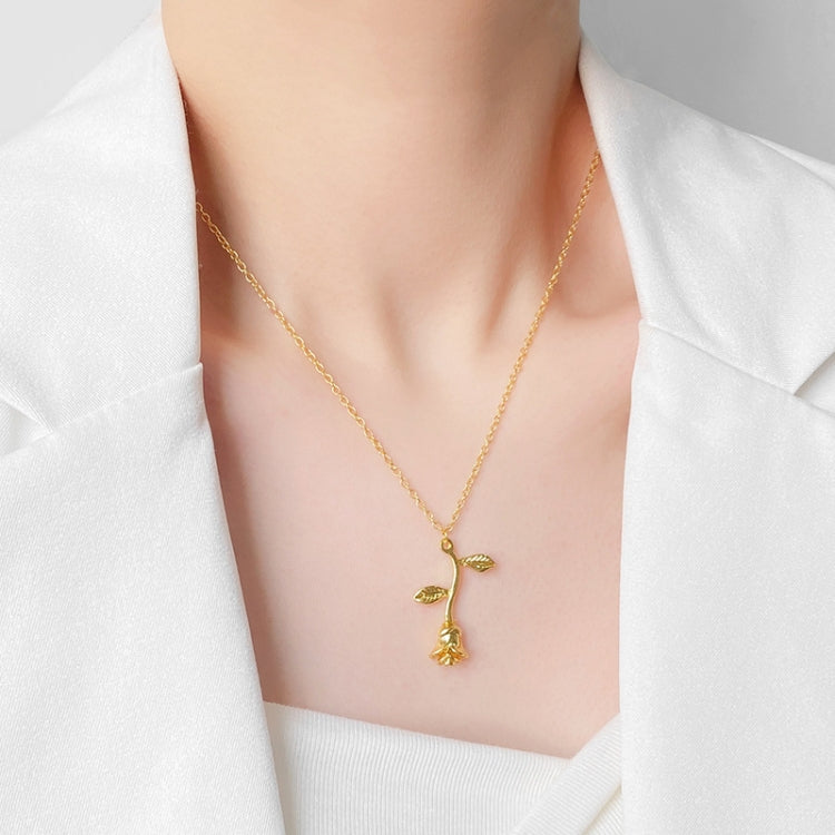 Gold-tone rose pendant necklace on model with branching floral charm and leaf accents