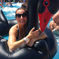 Black swan inflatable pool float ring with red beak, close-up with swimmers