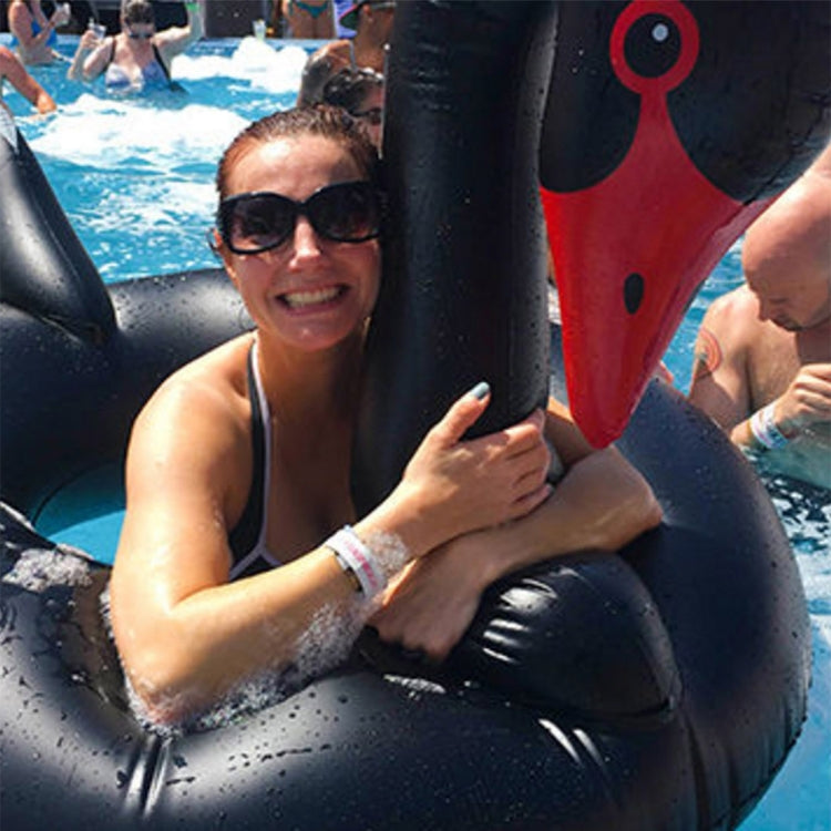 Black swan inflatable pool float ring with red beak, close-up with swimmers