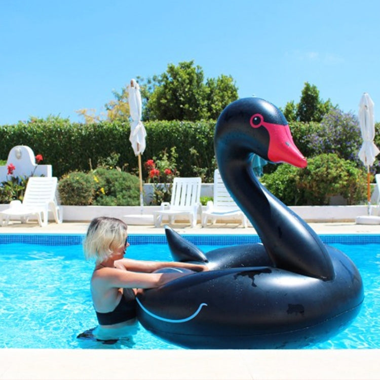 Black swan inflatable pool ring with red beak, floating with a child