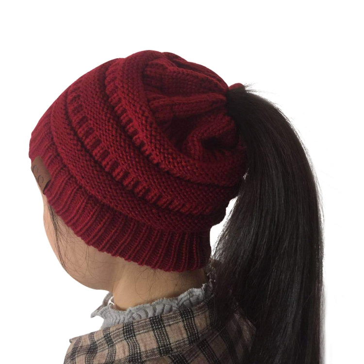 Burgundy red knitted ponytail cap beanie with ribbed cuff and cable-style knit