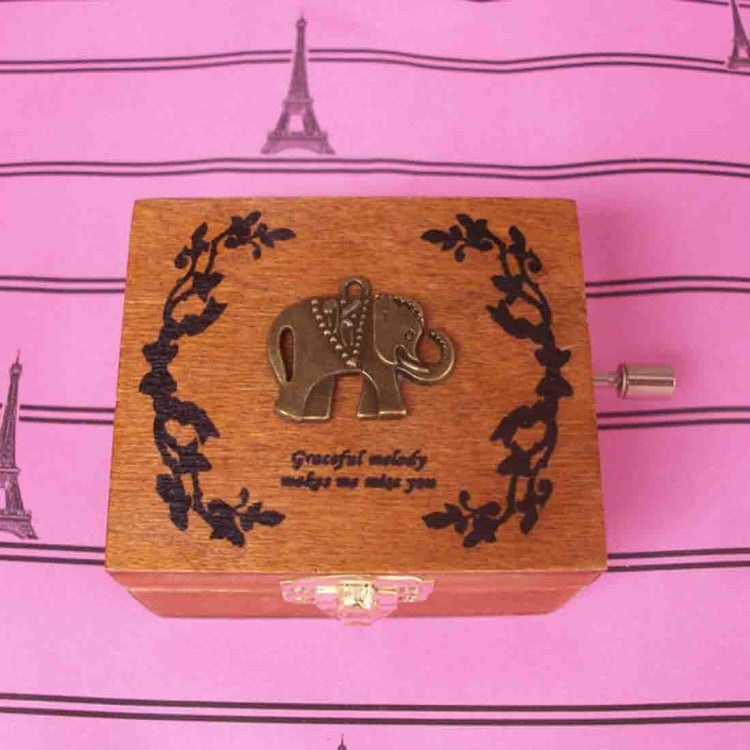 Wooden music box with ornate laurel engraving and elephant motif on the lid