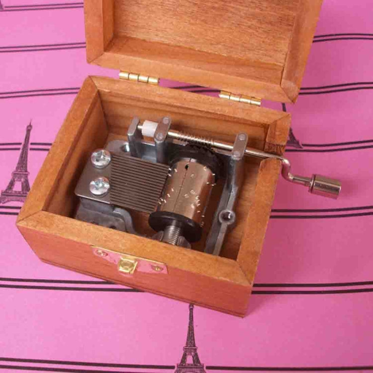 Open wooden music box showing metal music mechanism and winding handle