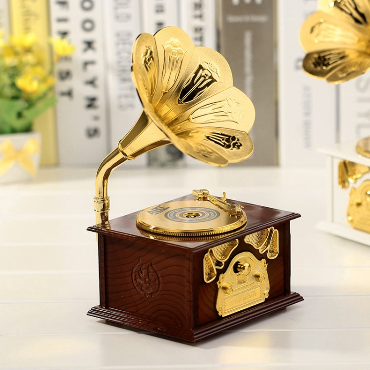 Gold-tone retro phonograph-style music box on dark wooden base with gramophone horn