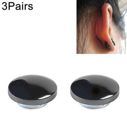 Round black magnetic therapy earring with silver edge, worn on an ear