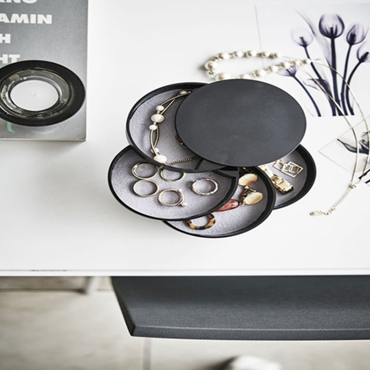 Black multi-tier jewelry storage case with round lid open on desktop