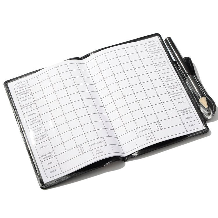 Open referee record notebook with grid pages and pencil in side holder