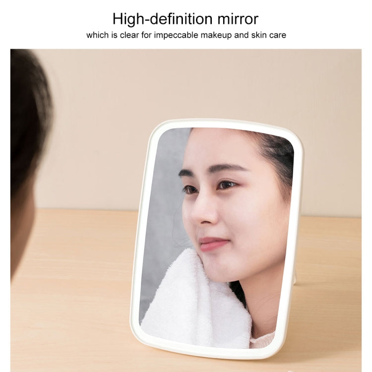 White-framed square LED cosmetic mirror reflecting a person for makeup