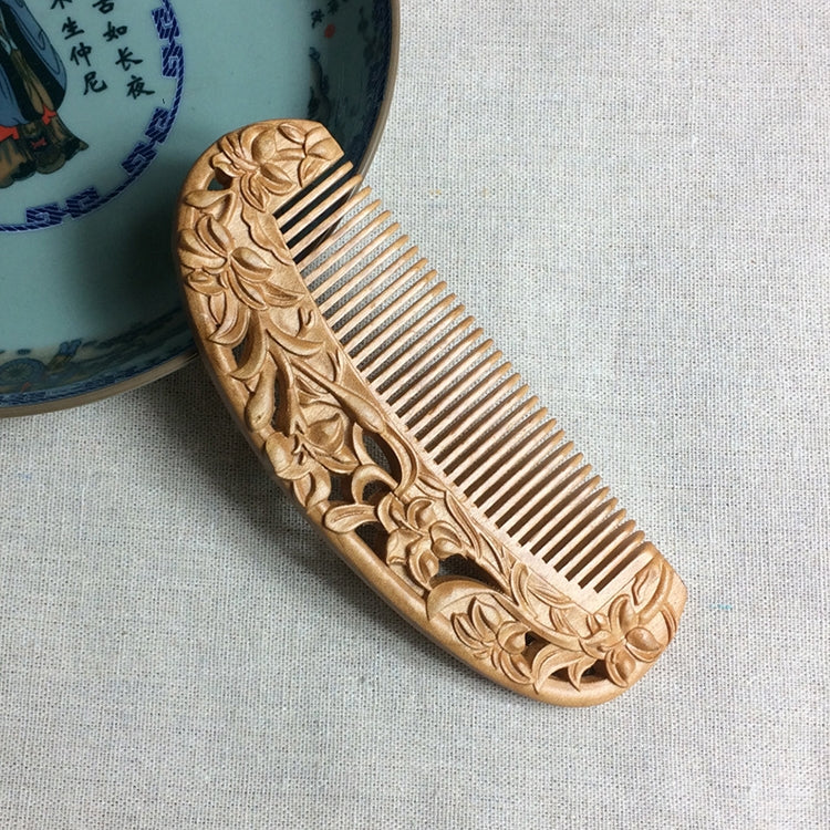 Carved wooden hair comb with straight teeth and floral scrollwork along the sides