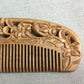 Close-up of carved floral wooden comb with straight teeth and detailed side scrollwork