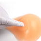 Silicone breast pad being placed into a bra cup by gloved hand, peach tone.