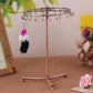 Rose gold rotating jewelry rack with hanging charms, tassels, and tripod base