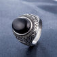 Men’s titanium steel ring close-up with dark oval gemstone and engraved silver scrollwork