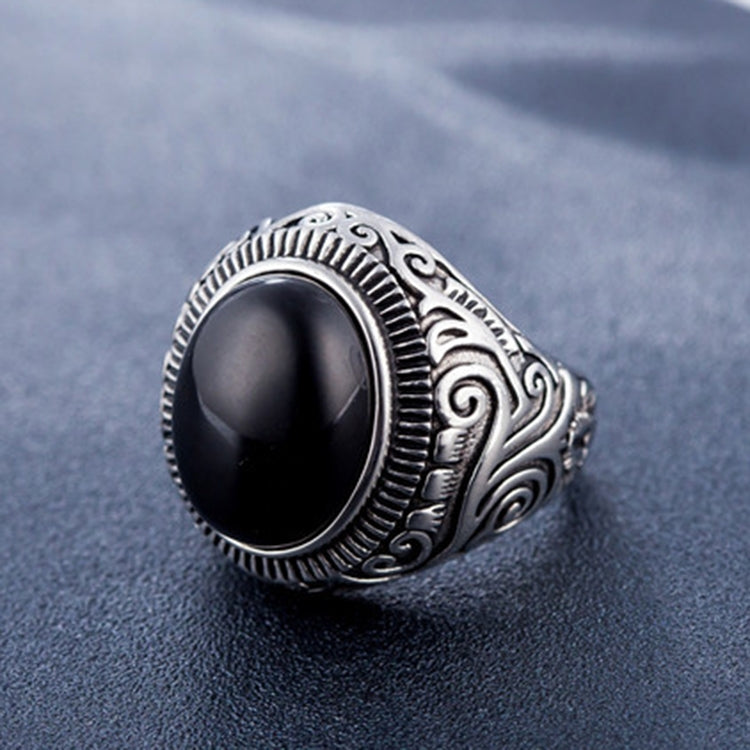 Men’s titanium steel ring with dark oval gemstone and patterned bezel, angled view
