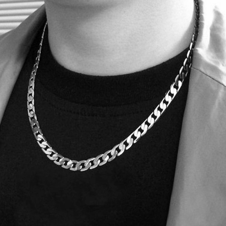 Silver chain necklace worn on a crew-neck top, thick curb-link design