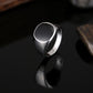 Silver-tone drip signet ring, black oval face, angled view