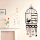 Black birdcage jewelry organizer with hooks and compartments holding necklaces and earrings