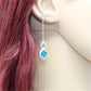 Silver-plated blue crystal drop earrings shown worn with clear top stones on chains