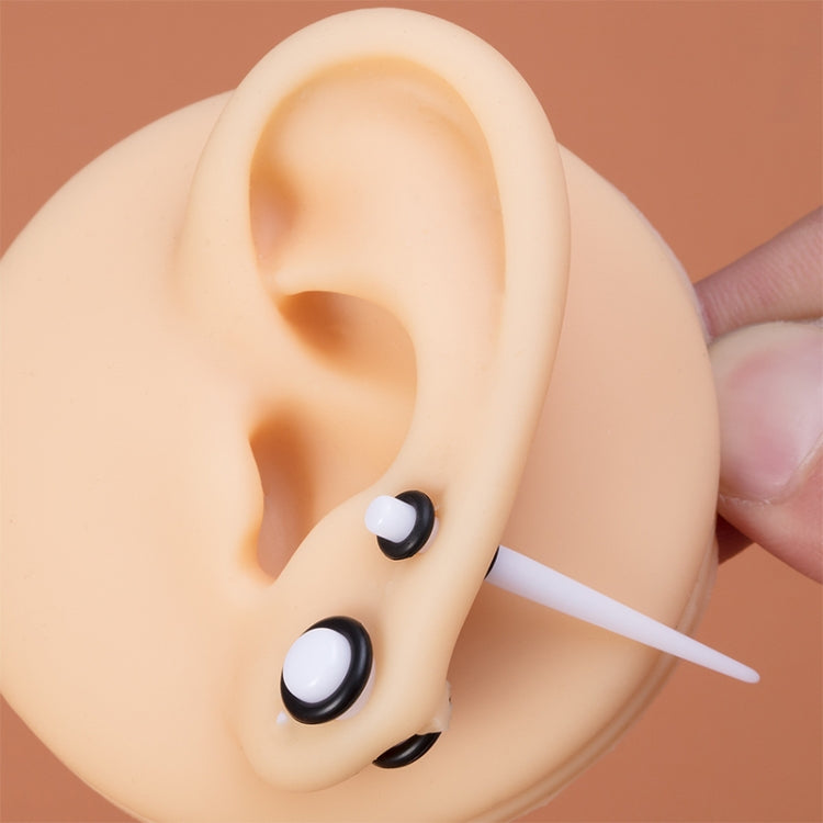 Acrylic ear plug set with black and white round plugs on a practice ear model