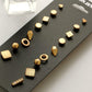 Close-up of gold-tone stud earring set with nine geometric studs on display card