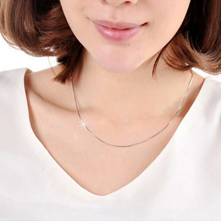 Thin silver plated snake bone chain necklace worn around the neck