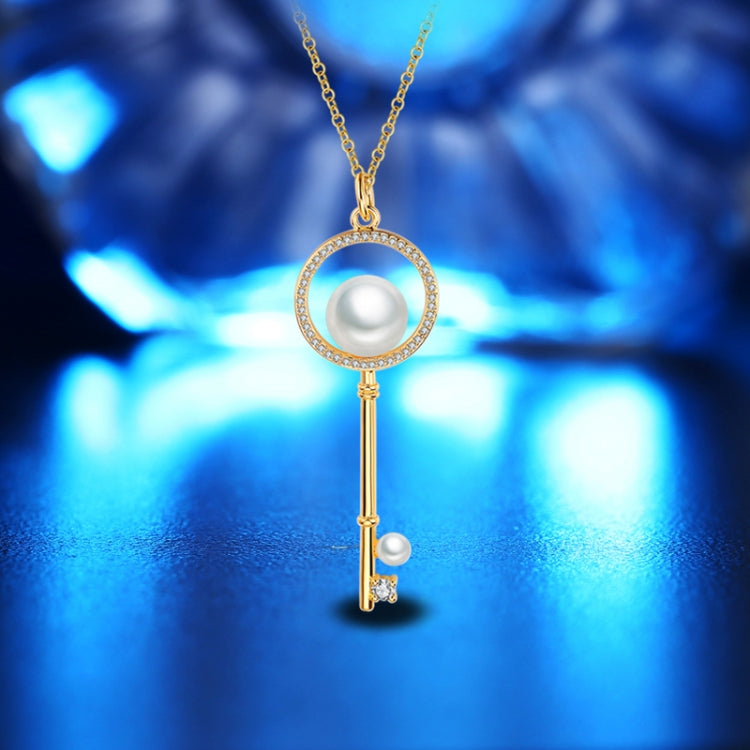 Gold key pendant necklace with round pearl, crystal halo, and dangling key charm